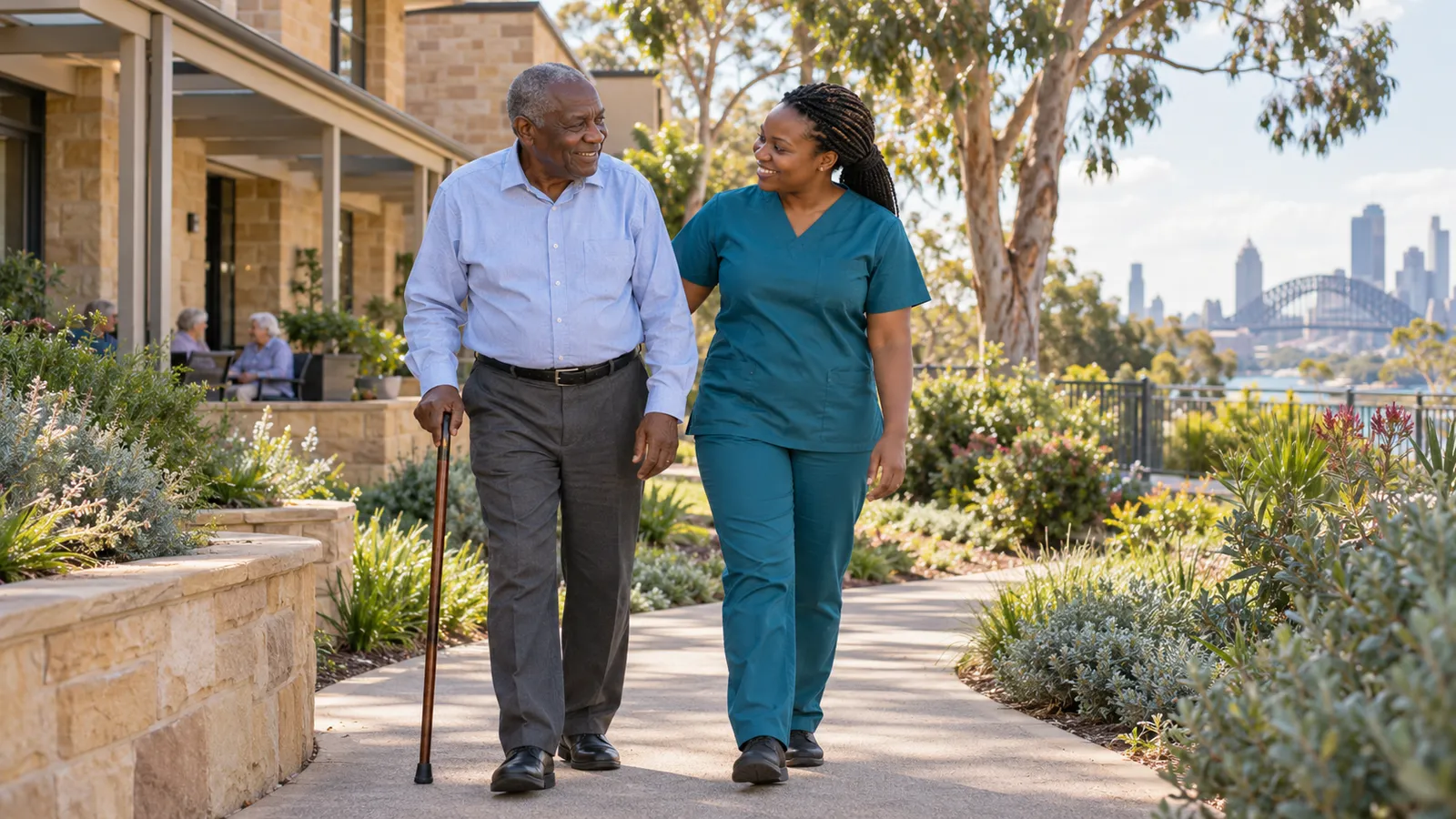 A Zimbabwean care worker walks beside an older man in a sunlit garden overlooking Sydney Harbour Bridge.